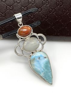 Larimar, White Moonstone and Sunstone Gemstone Sterling Silver Pendant Jewelry at Wholesale Price. SIZE : 3” X 1.45” ( including Bail) ( LXW ) *Width mentioned is at its widest * WEIGHT : 18.5g GEMSTONE : NATURAL MOONSTONE, LARIMAR AND SUNSTONE TREATMENT: NO TREATMENT METAL : 925 STERLING SILVER HANDMADE **All Measurements are close approximations** LARIMAR : Larimar is the embodiment of the tranquil Sea and Sky energies. Its soft, soothing blues and calming turquoise is streaked with white patt Moonstone And Sunstone, San Ramon, White Moonstone, Silver Jewelry Pendant, Pendant Silver, Turquoise Pendant, Wrapped Pendant, Turquoise Gemstone, Wire Wrapped Pendant