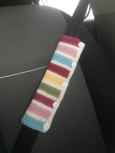 a colorful crocheted object sitting on the back seat of a car with buttons