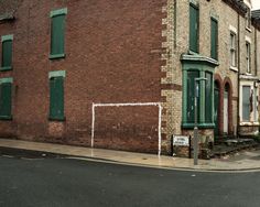 an old brick building with green shutters next to a street