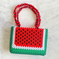 a red, white and green beaded purse sitting on top of a marble counter