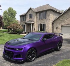 a purple chevrolet camaro parked in front of a house