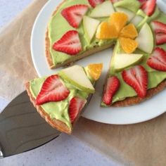 a white plate topped with a slice of cake covered in sliced strawberries and avocado