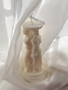 a candle that is sitting on some white fabric with a stick sticking out of it