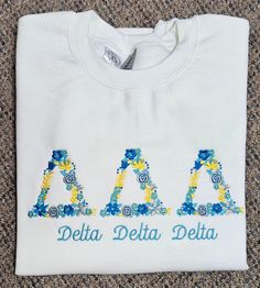 a white t - shirt with the word delta delta embroidered on it