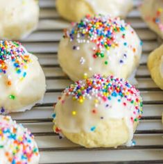 white frosted cookies with sprinkles on a cooling rack