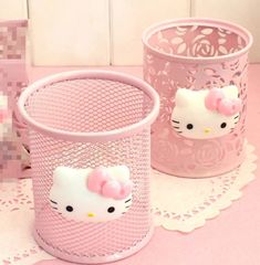 three pink hello kitty containers sitting on top of a white doily covered table next to each other