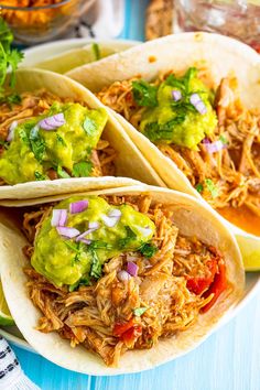 three shredded chicken tacos with guacamole and salsa