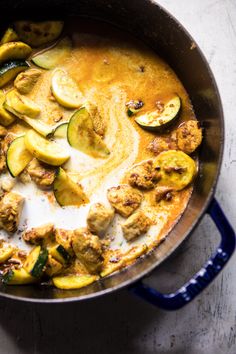 a pan filled with chicken and zucchini on top of a white countertop