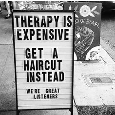 black and white photograph of a sign that says therapy is expensive get a haircut instead we're great listeners