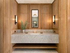 a bathroom with two sinks and mirrors in the wall, along with wooden paneling