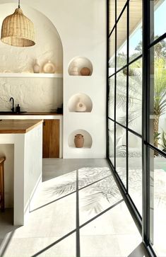 an open kitchen with white walls and flooring next to a large glass door that leads to the outside patio