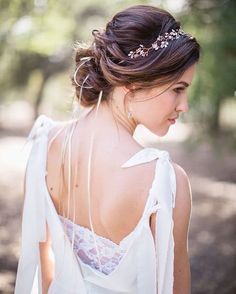 the back of a woman wearing a white dress and a headpiece with flowers on it