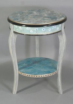 a white table with blue and black designs on the top, sitting against a gray background