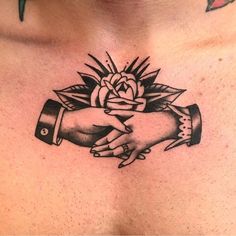 a close up of a person's chest with a rose on it and two hands holding each other