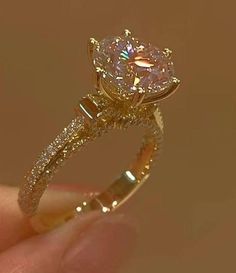 a woman's hand holding a yellow gold engagement ring