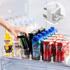 an open refrigerator with drinks and sodas in the freezer compartment, being held by someone's hand