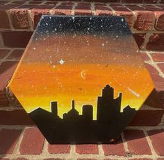 a painted hexagonal object on the side of a brick wall with a cityscape in the background