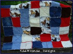 a quilt with horses on it is sitting on a wooden bench in front of some grass