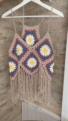 a crocheted crop top hanging on a hanger next to a radiator