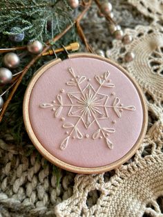 a pink snowflake ornament hanging from a christmas tree with ornaments around it