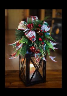 a christmas decoration in a lantern with holly and candy canes on the top, sitting on a wooden table