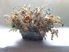 a basket filled with lots of flowers sitting on top of a white table covered in sunlight