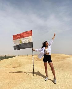 a woman holding a flag on top of a dirt hill