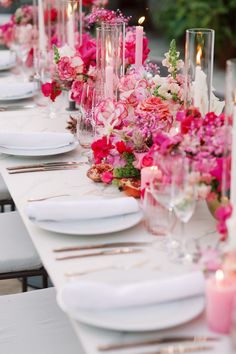 a long table with white plates and pink flowers