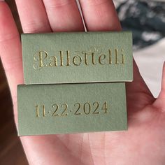 two tags that say pallottelli and 1232 are in the palm of a person's hand