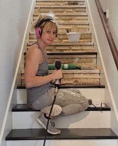 a woman with headphones sitting on top of a set of stairs holding a microphone