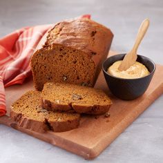 a loaf of bread sitting on top of a cutting board next to a bowl of peanut butter