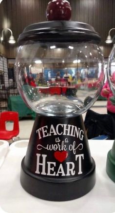 there are two snow globes that say teaching is a work of heart on the table