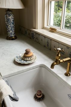 a white sink sitting under a window next to a lamp