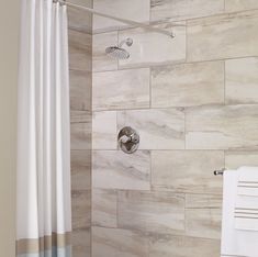 a bathroom with a shower, towel rack and toilet paper roll on the wall next to it