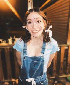 a young woman wearing overalls and smiling at the camera