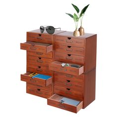 a wooden cabinet with many drawers and sunglasses on top of it next to a potted plant