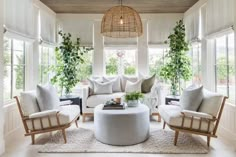 a living room with couches, chairs and plants in the window sill area