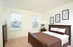 a bedroom with a bed, dresser and two pictures on the wall above it's headboard