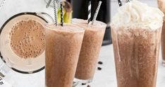 three glasses filled with ice cream and chocolate milkshakes on top of a table