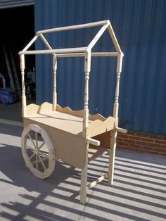 an old fashioned wagon is sitting in front of a blue building with a white roof