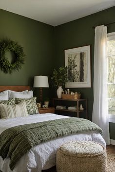 a bedroom with green walls and white linens on the bed, along with an ottoman