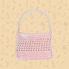 a crocheted pink purse with white handles on a yellow background and floral designs