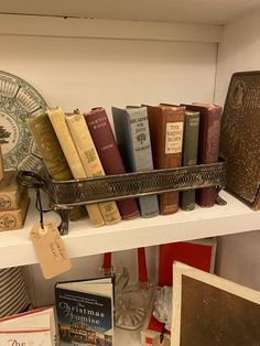 a shelf filled with lots of books on top of a white shelf next to other items