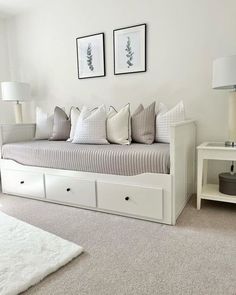 a living room with white furniture and two framed pictures on the wall above the couch