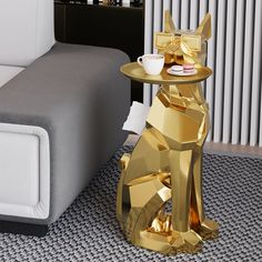 a gold dog table with a cup on it next to a couch and coffee table