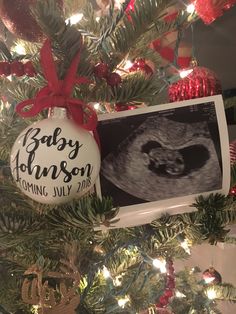 an ornament hanging from the christmas tree with baby johnson on it's belly