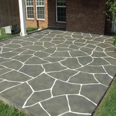 a concrete patio in front of a brick house with white lines painted on the cement