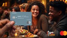 people sitting at a table with food and drinks in front of them, while holding up a credit card