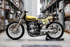 a yellow and black motorcycle is parked in a warehouse with pallets on the floor