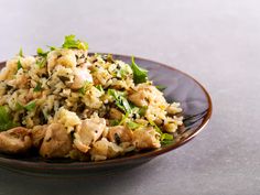 a brown plate topped with rice and meat covered in green leafy toppings on top of a table